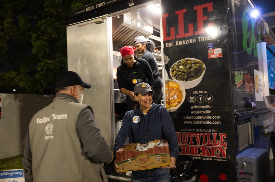 An image of José Andrés, Kim Prince, and others serving good from the back of the Hotville Chicken food truck